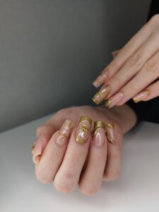 Manicure z perłowym podkładem ze złotymi malowaniami