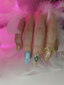 piękne manicure z niebieskimi i złotymi ozdobami i złotą obrączką